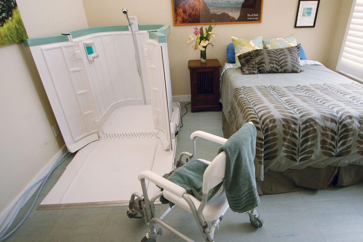 Home bedroom setup featuring a Shower Bay portable bathing unit and mobility chair, ideal for safe, private, and comfortable in-home showering.