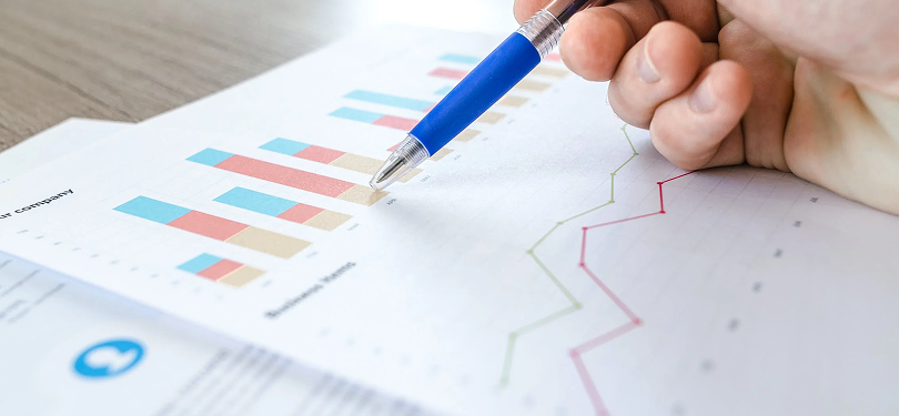 Close-up of someone pointing at graphs with a pen.
