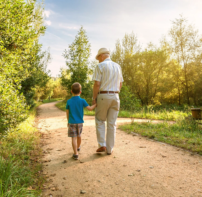 A grandchild and grandparent walking on a dirt path.