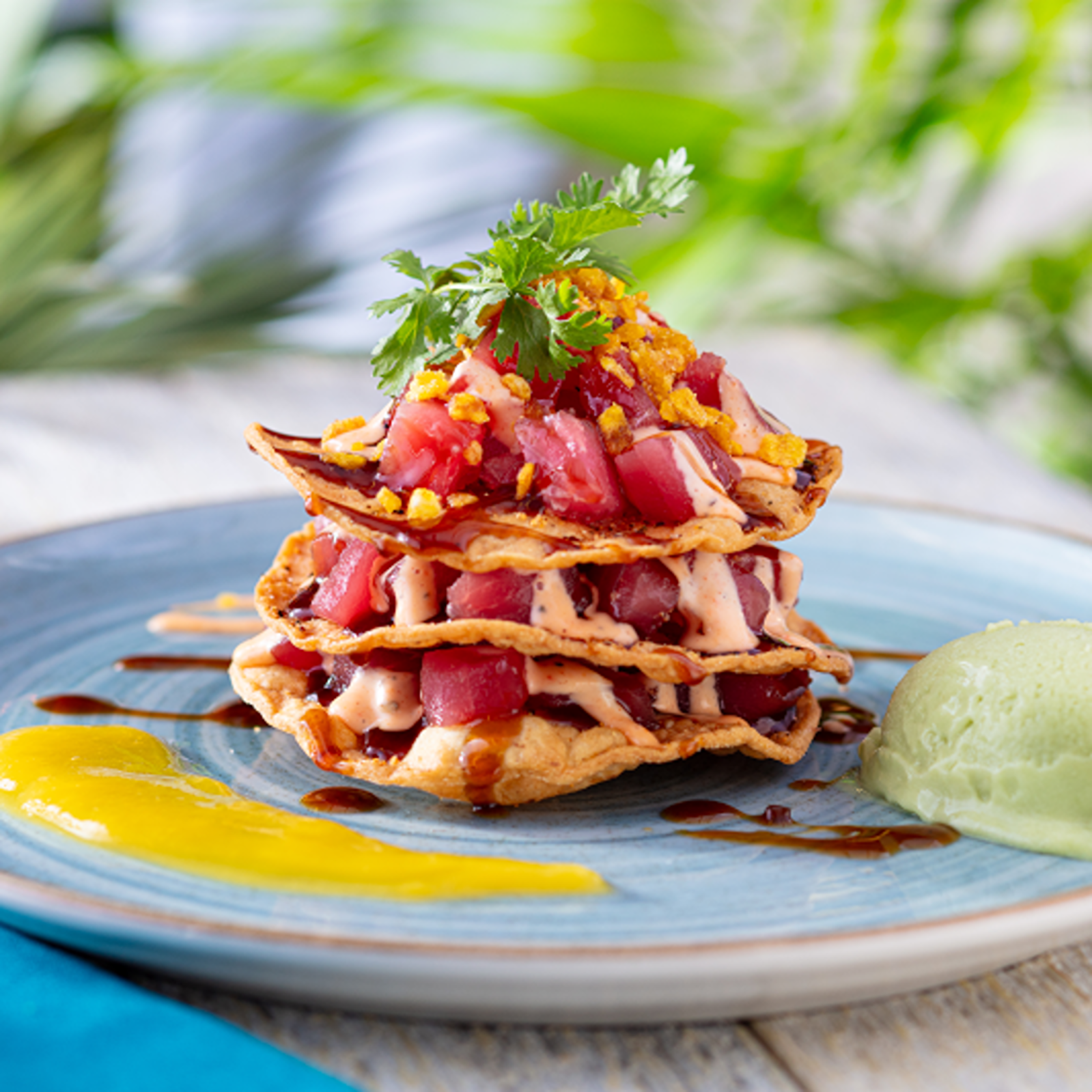 Tuna Tostada Stack - Ahi tuna poke layered with crispy tortillas, drizzled with a zesty lime aioli, served with an avocado lime sorbet.
