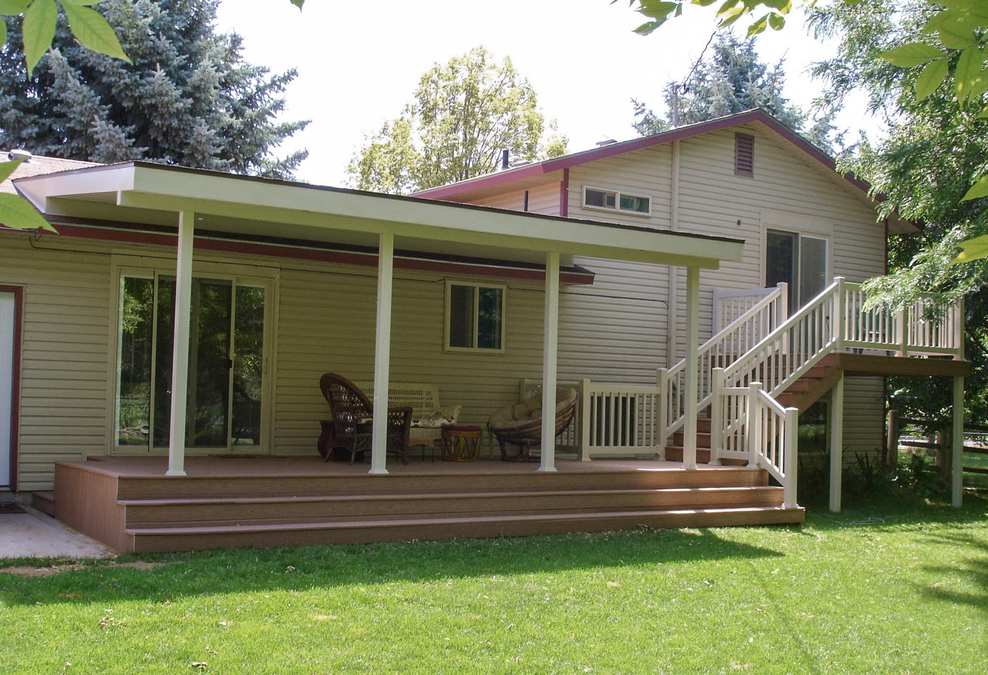 Create your dream outdoor oasis with a custom multi-level deck from DeckPro LLC. This expansive project features durable brown composite decking and a large, solid white patio cover, providing a perfect shaded retreat for relaxation and entertaining, rain or shine. The design includes an upper-level balcony and wide steps leading down to the main patio area, all finished with clean white vinyl railing.