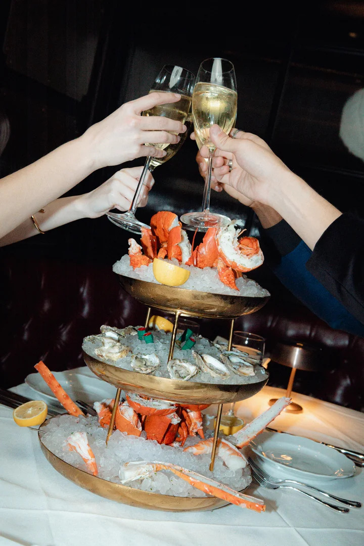 Group toasting with champagne over a seafood tray