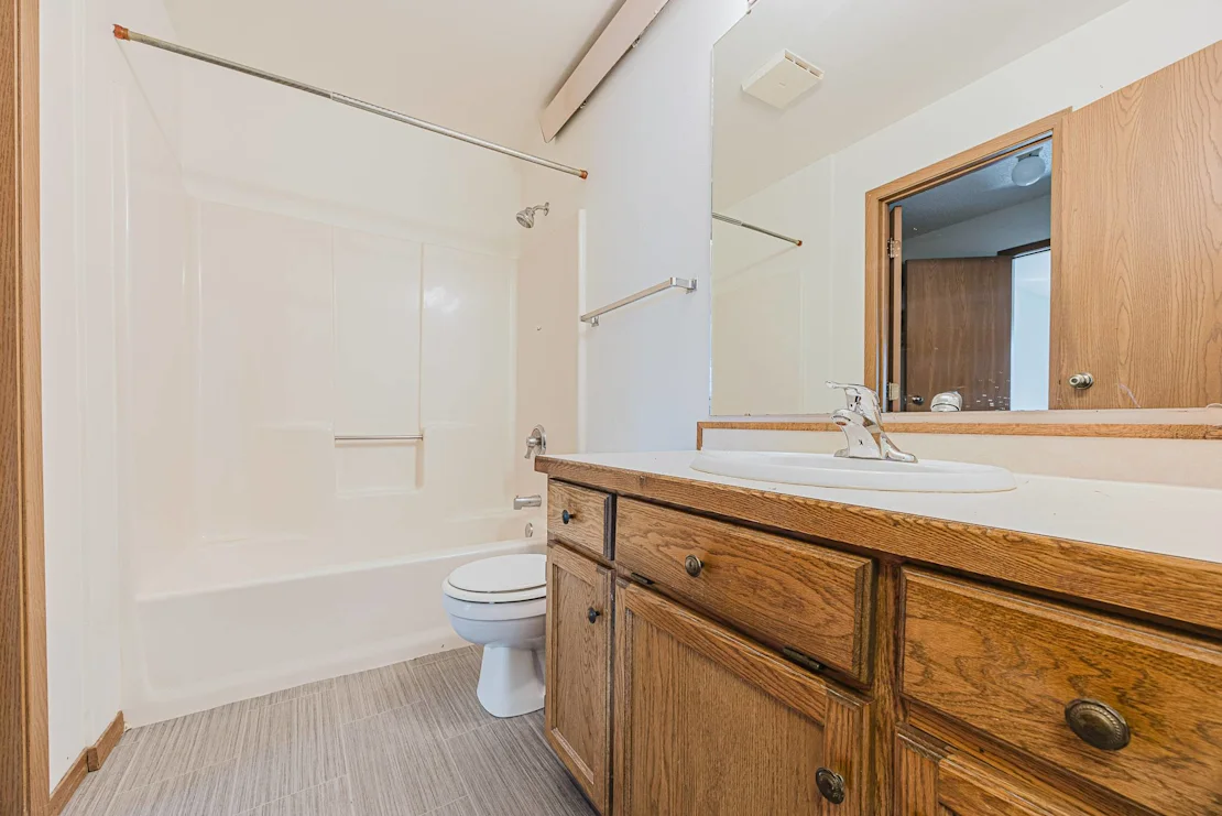 A bathroom with a toilet, sink, and mirror, Pine Pointe Apartments, Fargo, ND, 58104