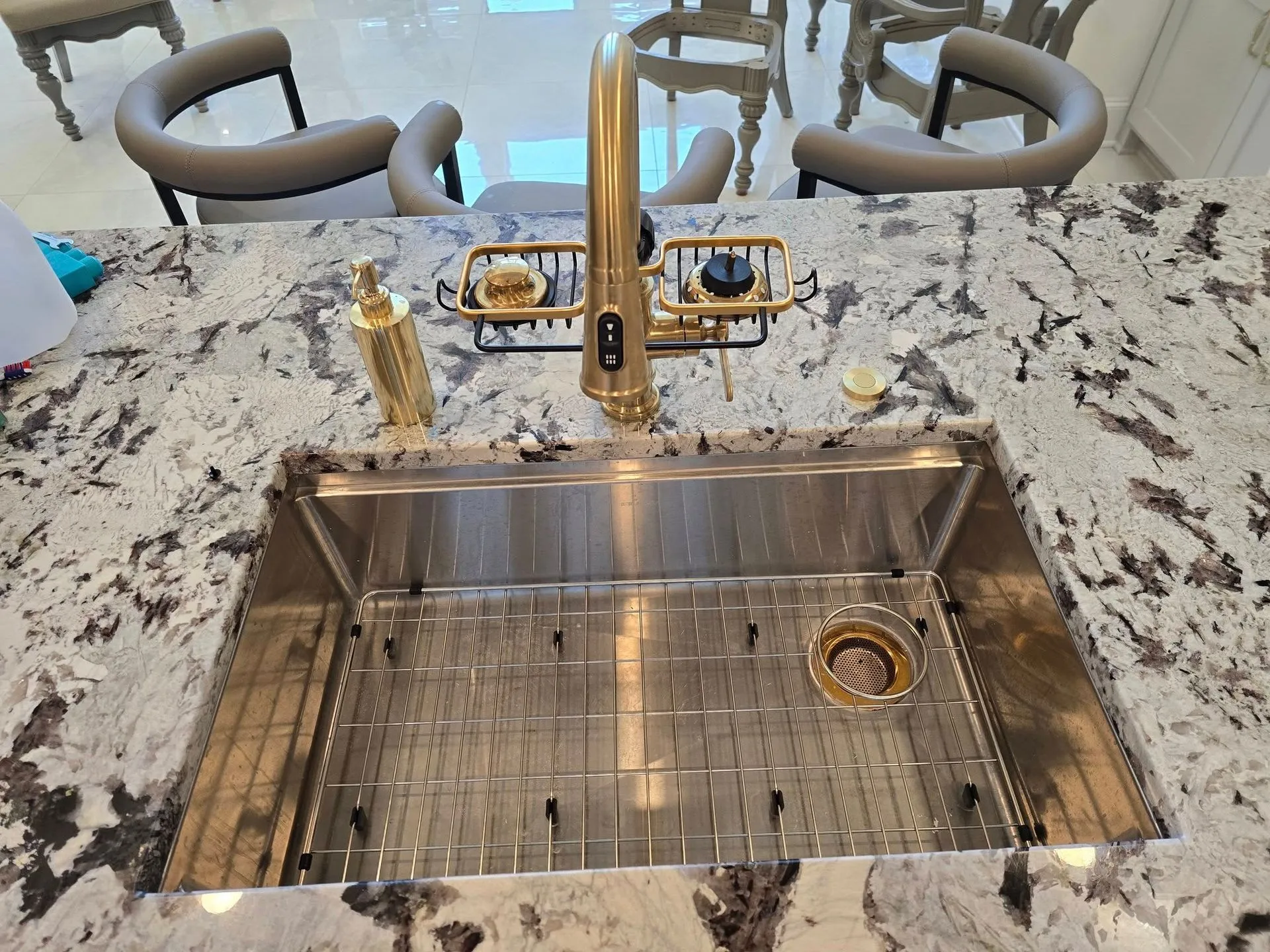 Elegant stainless steel farmhouse sink paired with brushed gold faucet and granite countertop showcases premium kitchen plumbing installation, combining modern functionality, stylish fixtures, and exceptional residential craftsmanship for homeowners.