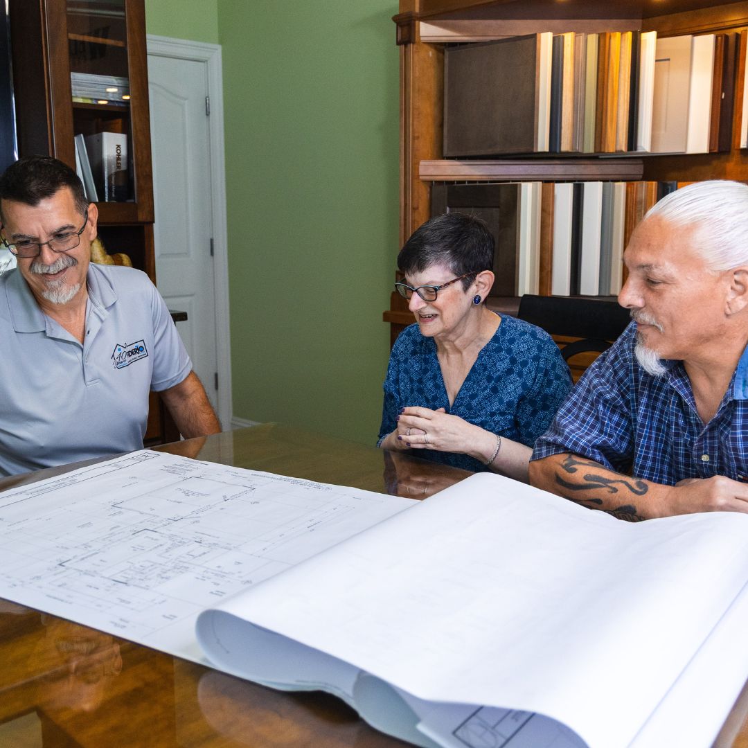 Fiderio project lead and clients sit together to discuss remodeling plans laid out in blueprint form.
