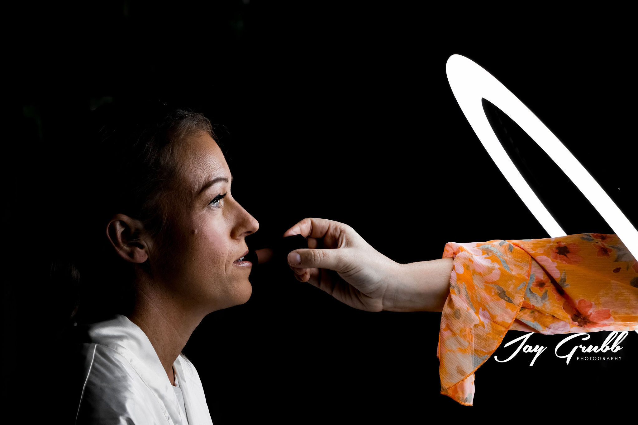 artists photo of hand holding makeup through light 