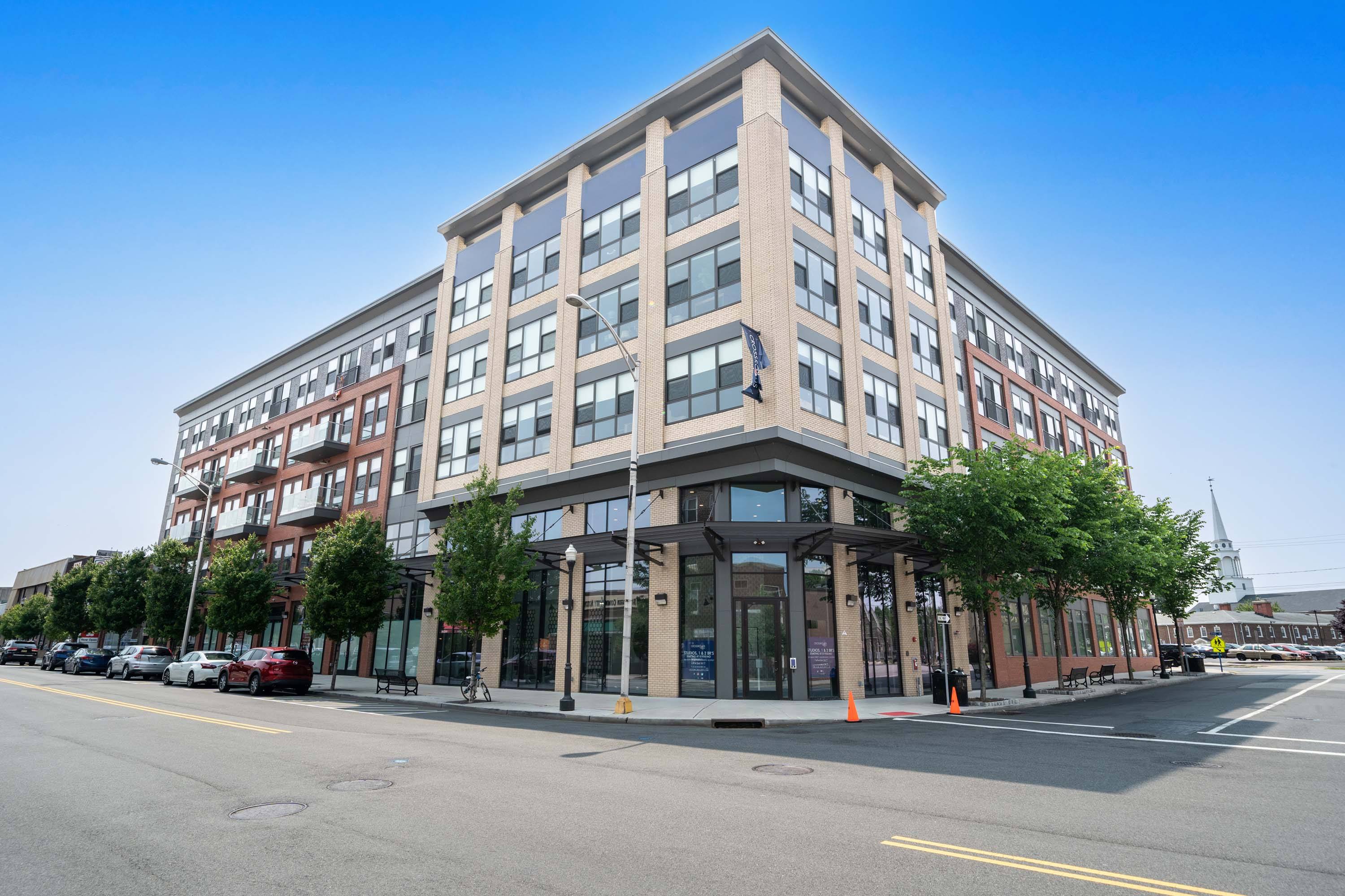 A modern multi-story building with a parking lot in front