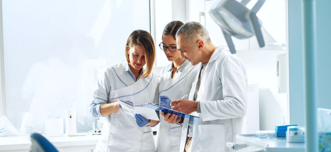 Three medical professionals huddled together in their office.