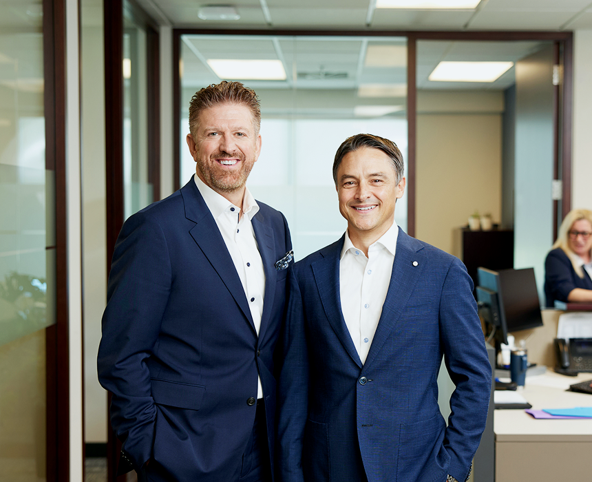 Jean Marchand and Patrice Filiatrault posing with their team in the background.