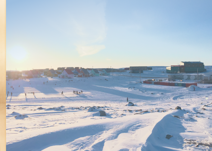 A snowy field surrounded by homes.