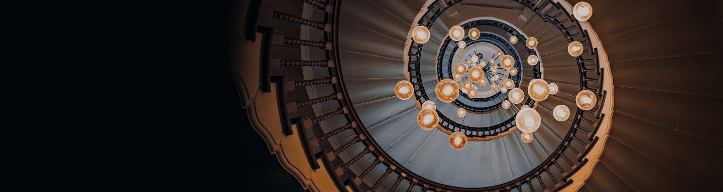 A bottom-up view of a spiral staircase and chandelier.