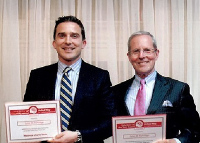 Peter Partridge and his dad smiling and holding awards from United Way Niagara.