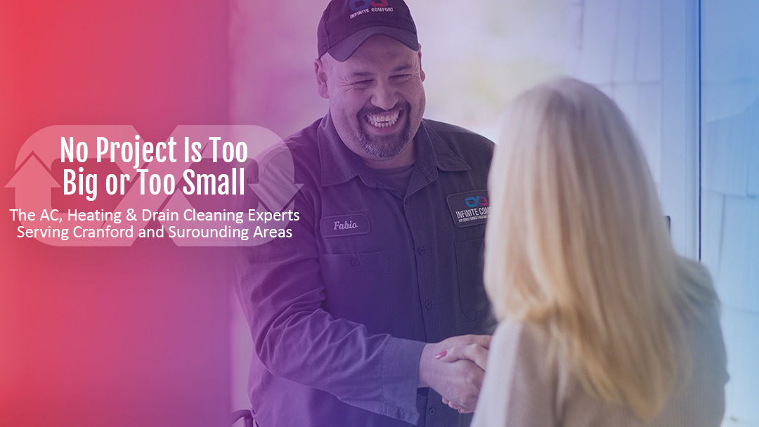 A smiling HVAC technician in uniform shakes hands with a client. The technician wears a black cap and a dark gray uniform with the company logo and his name, "Fabio," embroidered on it. The company logo is visible on his shirt pocket and reads "INFINITE COMFORT AIR CONDITIONING HEATING & MORE". The text overlay on the left side of the image reads "No Project Is Too Big or Too Small. The AC, Heating & Drain Cleaning Experts Serving Cranford and Surrounding Areas." The background is a soft blur with a gradient of pink to purple to blue.