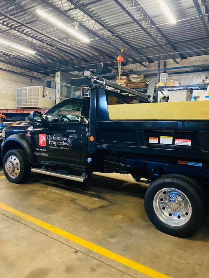 Performance Properties LLC branded service truck parked inside a commercial warehouse facility. The vehicle represents professional property maintenance, facility management, construction support services, and reliable transportation solutions for residential and commercial property operations and maintenance projects.