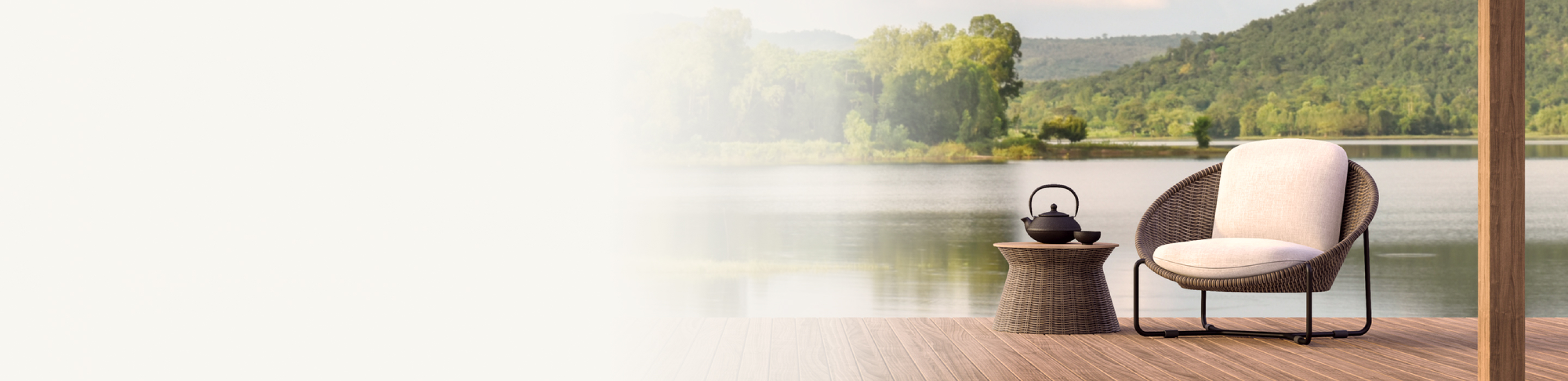 A wicker armchair on a dock by a gorgeous lake surrounded by trees.