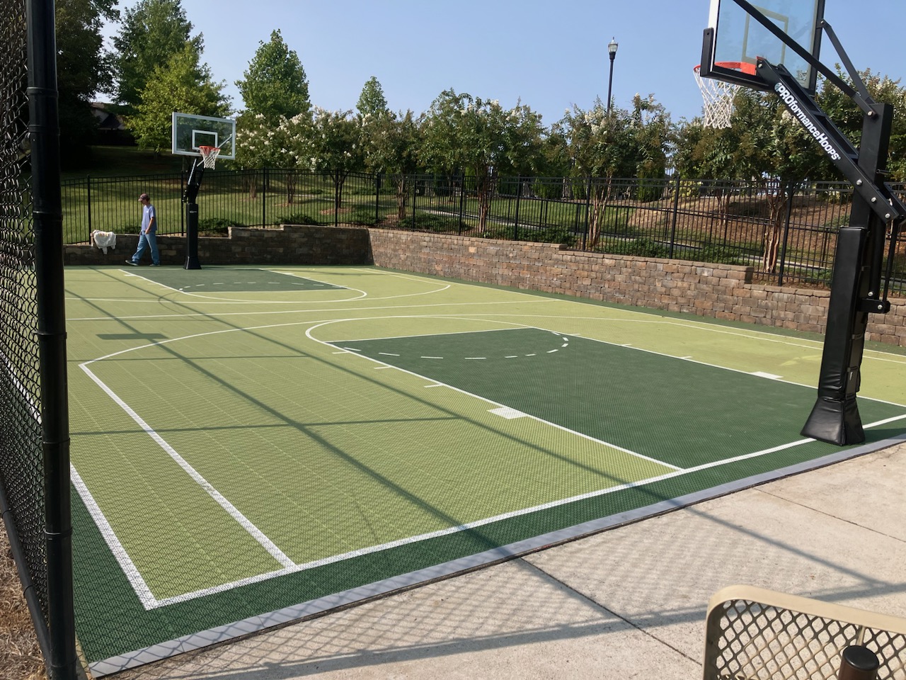 Full outdoor basketball court with green multi-sport tiling.