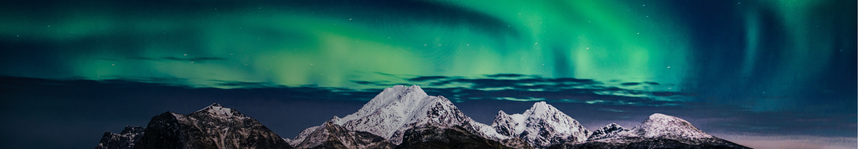 The aurora borealis lighting up the sky above a snow-capped mountain range.