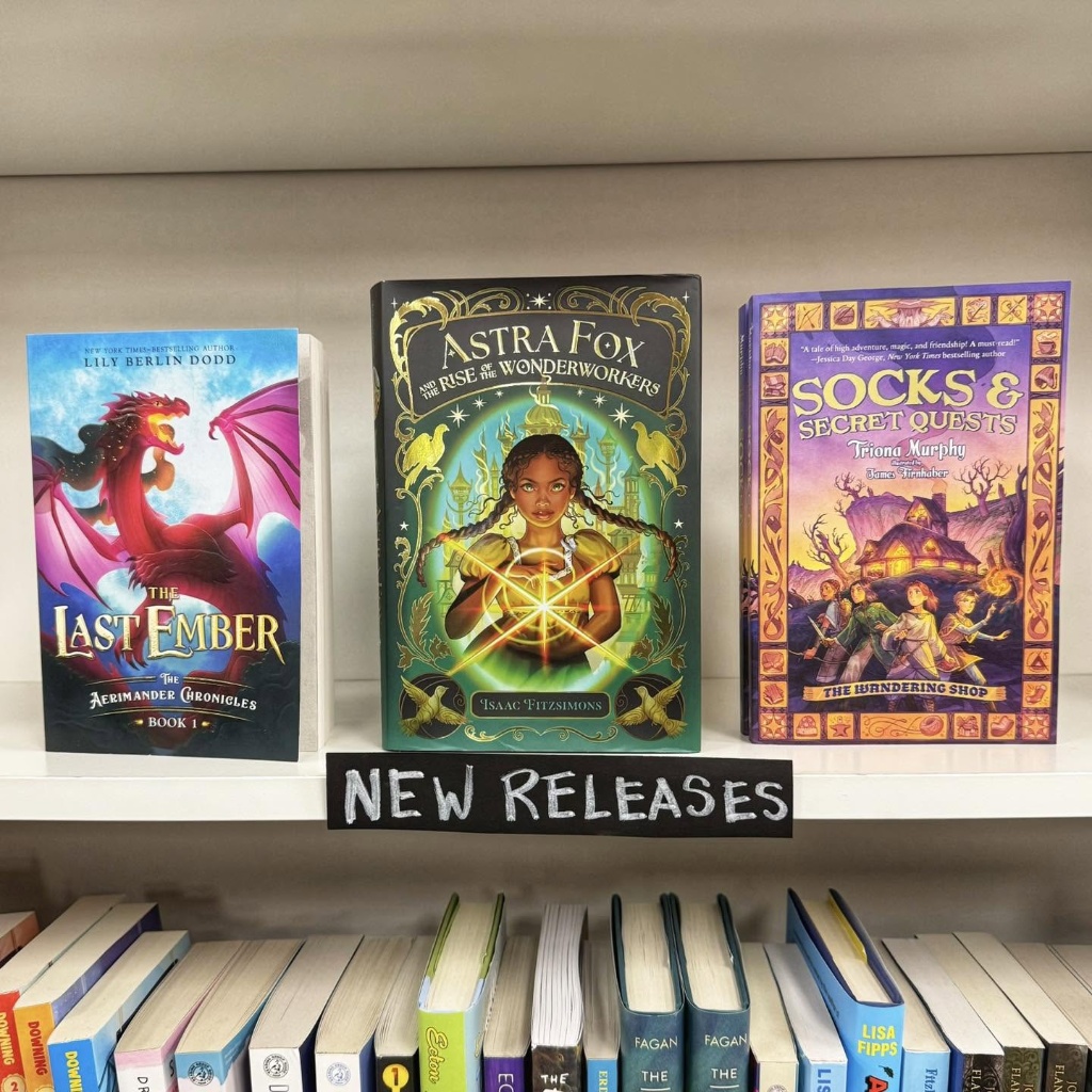Three magical new-release middle-grade books displayed on a shelf under a 'New Releases' sign at Content Bookstore, featuring 'The Last Ember', 'Astra Fox', and 'Socks & Secret Quests'