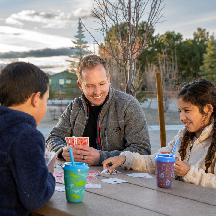 Family playing cards at a private picnic table at Little America's RV park.