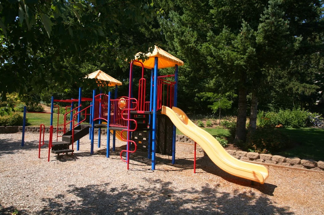 A playground with a yellow slide and red and blue structures