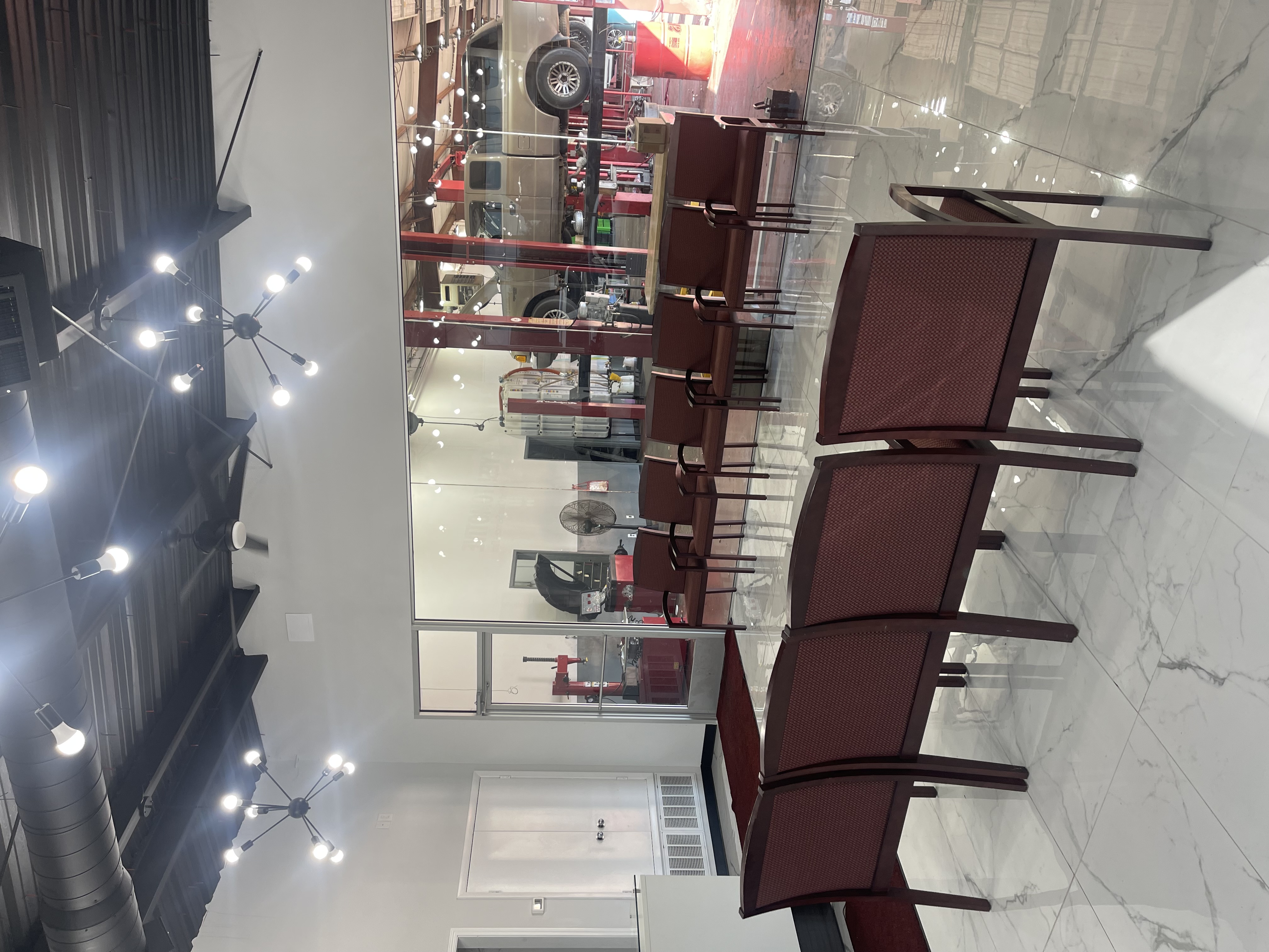 Clean customer waiting lobby at Yes! Automotive in Houston, Texas, featuring large glass windows offering a clear view directly into the service bay area.
