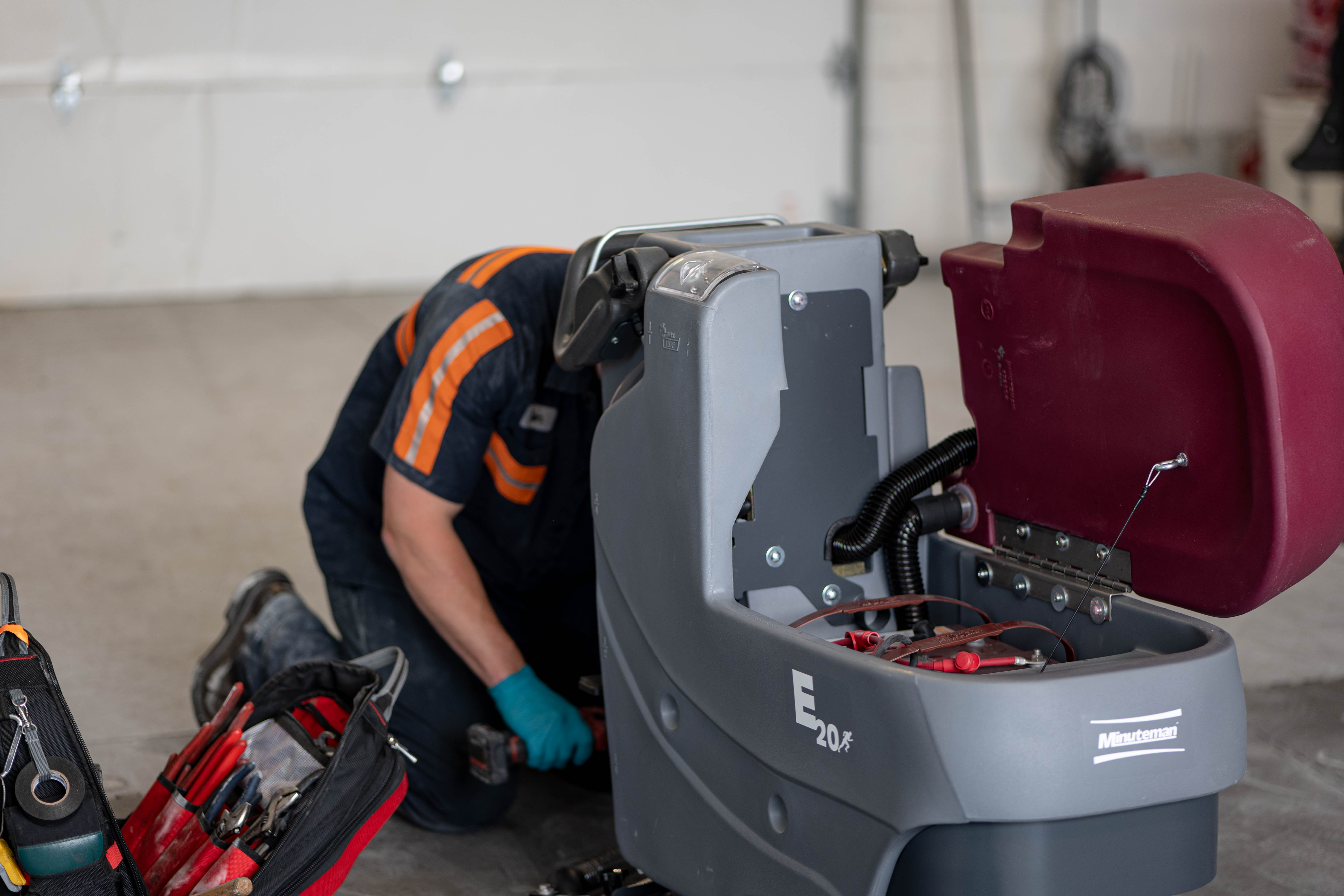 A WaySolutions field technician reaches deep into the internal chassis of a Minuteman E20 walk-behind floor scrubber to perform a comprehensive mechanical repair. Equipped with professional toolkits, our local Layton, Utah experts dismantle what is necessary to guarantee a permanent, reliable fix for your heavy-duty equipment.