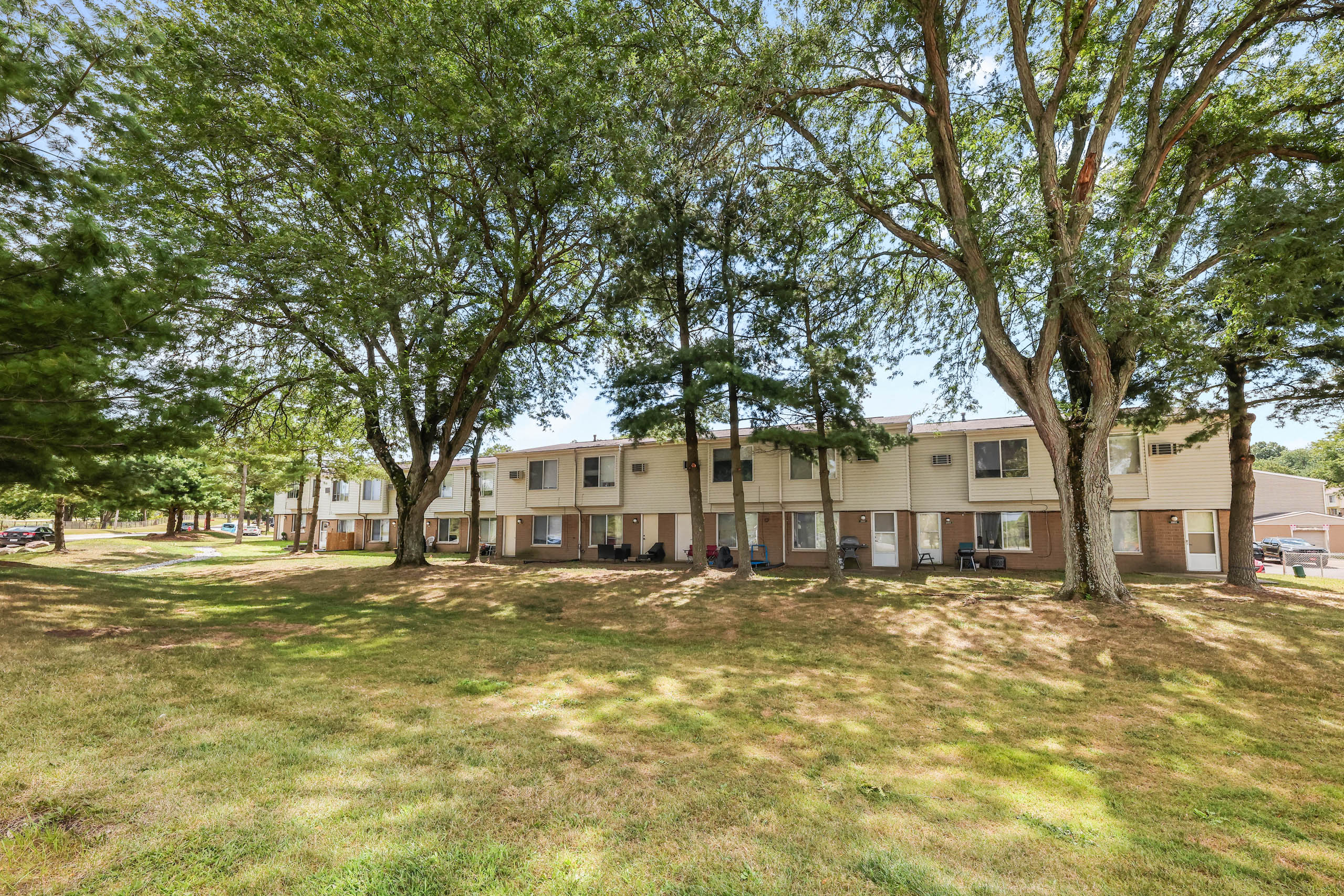 A grassy area with trees and apartment buildings in the background
