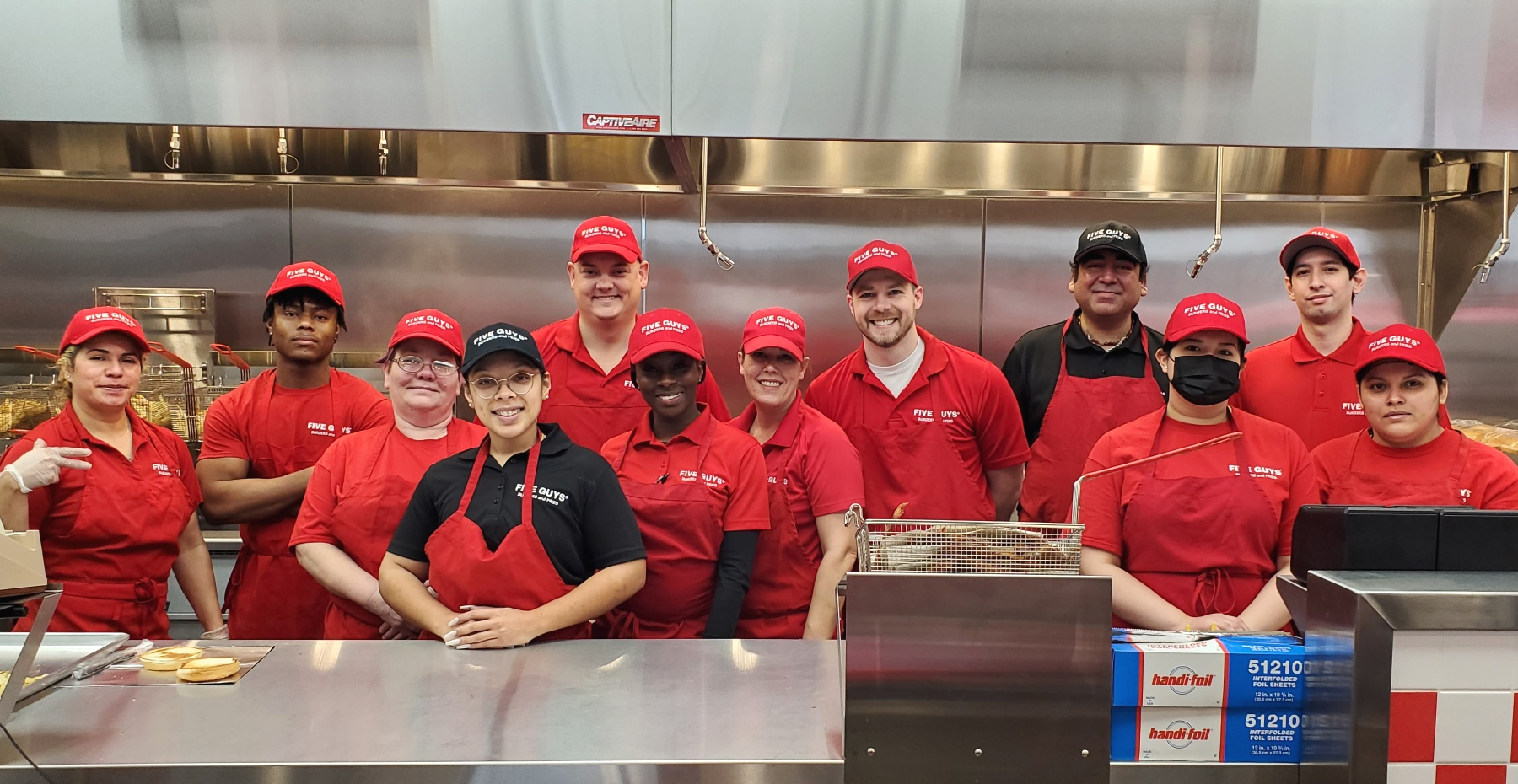 Employee pose for a photograph in the kitchen ahead of the grand opening of the Five Guys restaurant at 44795 Dulles Overlook Drive in Ashburn, Virginia.