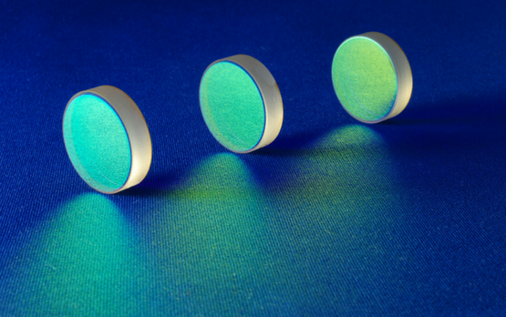 Three precision notch filters with green wavelength blocking characteristics manufactured by Deposition Sciences. These specialized coatings block specific wavelength bands while transmitting both shorter and longer wavelengths, essential for CO₂ absorption blocking in thermal imaging systems, laser protection eyewear, and Raman spectroscopy applications in aerospace and scientific instrumentation.