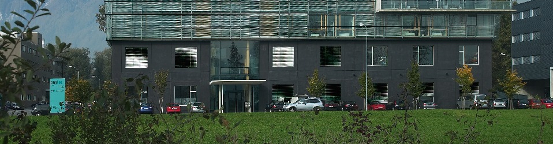 Wiese und Gebäude mit Glasfassade und Spezial-Lichtlenk-Jalousien.