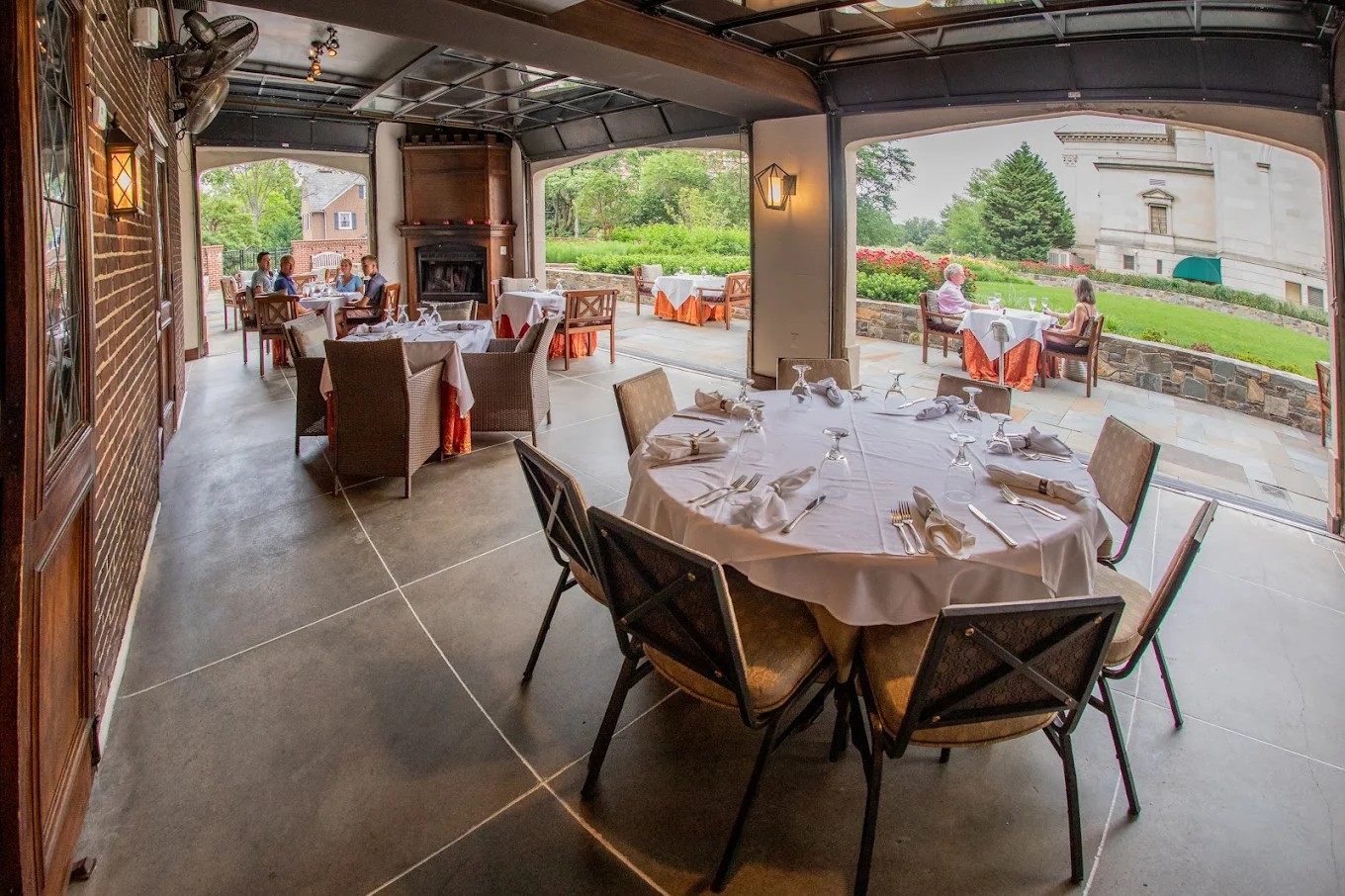 A sophisticated dining space with indoor-outdoor seating, crisp white linens, and a serene garden vi 