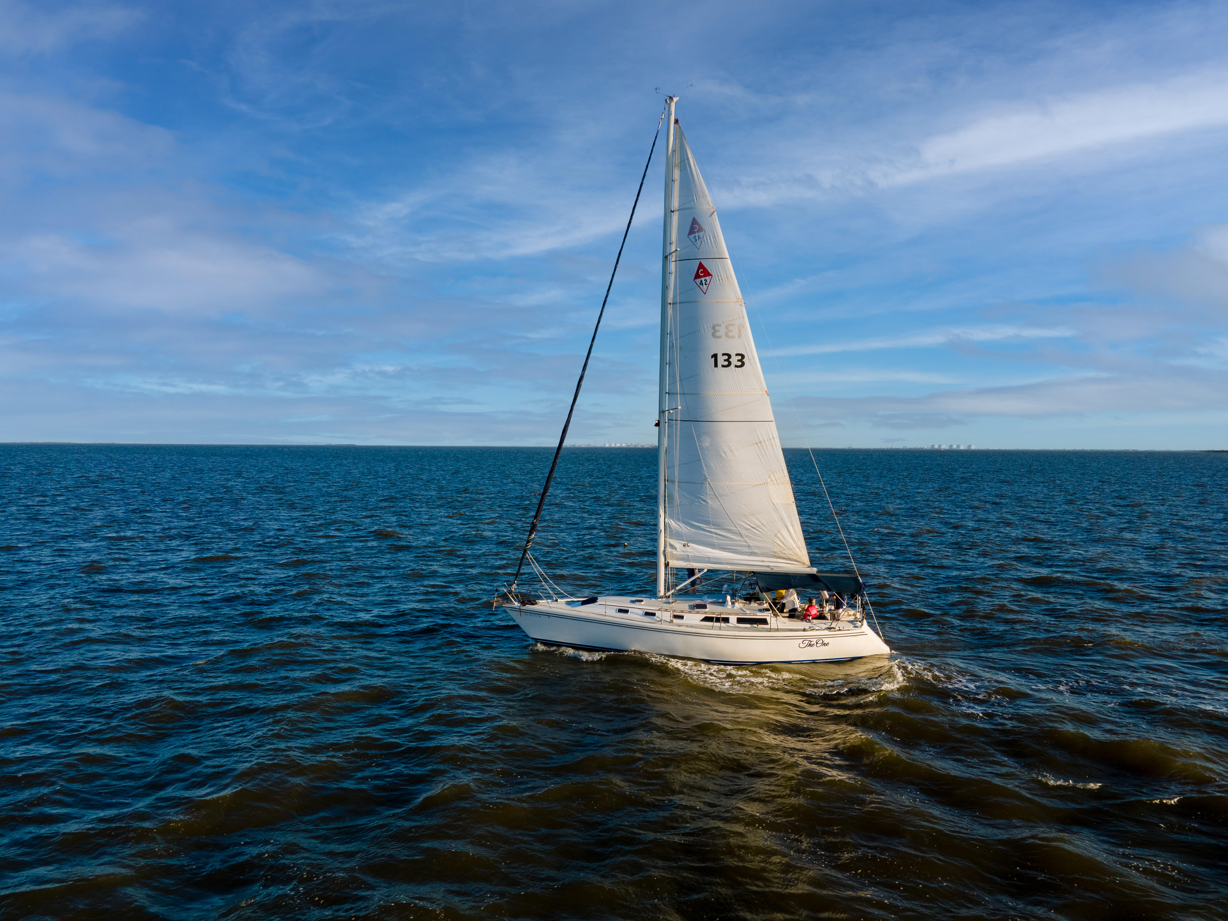 a sailboat sails away from the Pleasure Island Marina and Port Arthur Yacht Club on Sabine lake in Port Arthur