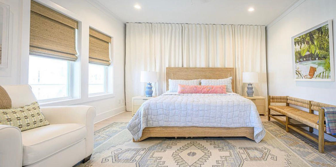 Feel like you're on vacation everyday in resort style room by adding Woven Wood Shades and white Drapery to you bedroom. Budget Blinds of Rockwall, Terrell, and Greenville's team can help you design the perfect window solution for you!