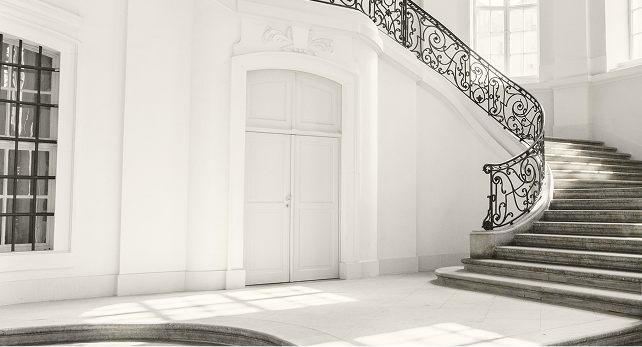 Grand staircase with ornate railings in a white entryway.