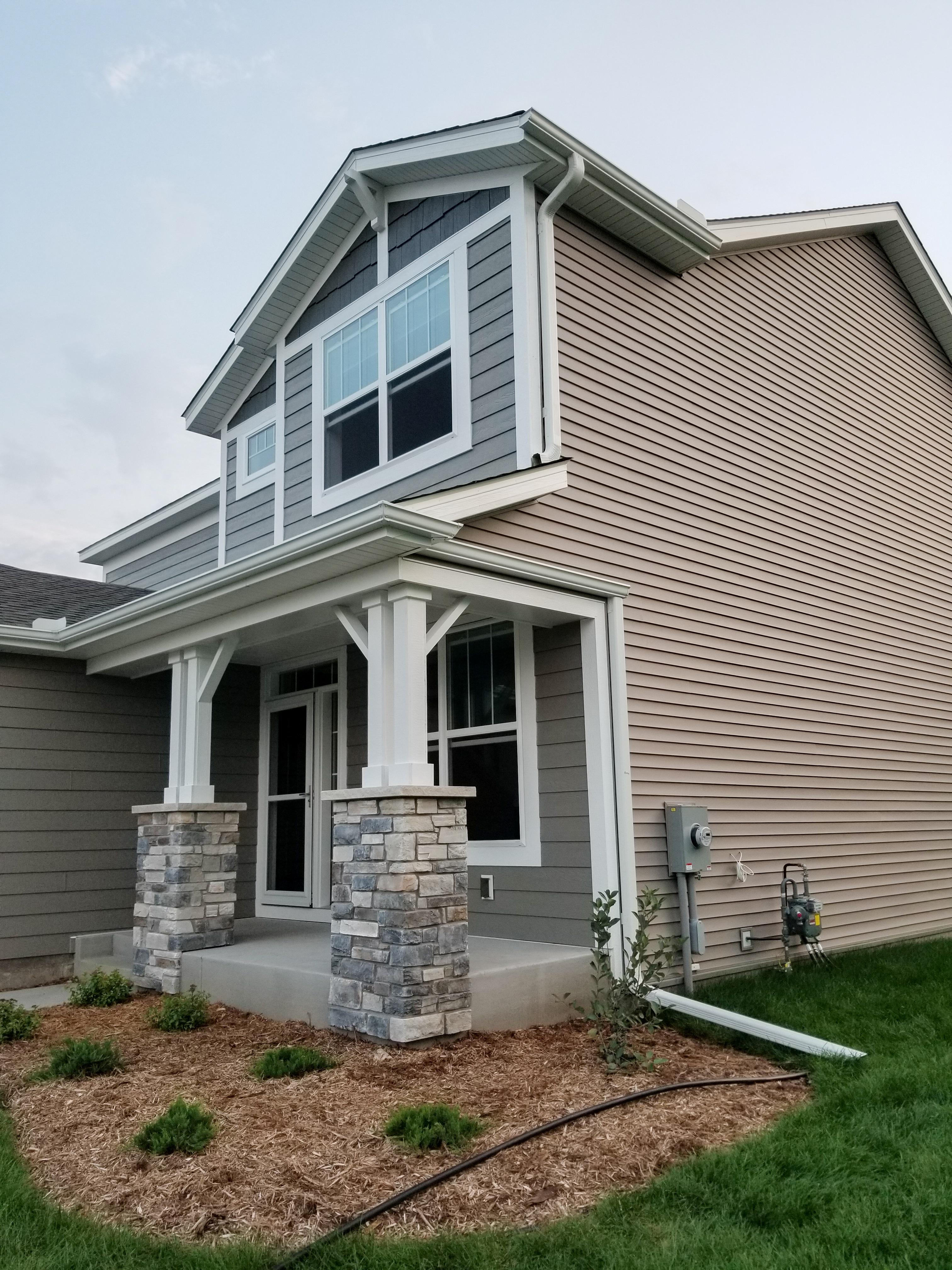 White seamless gutters and a downspout with an extension installed on a modern home's front porch by Ultimate Gutter Solutions.