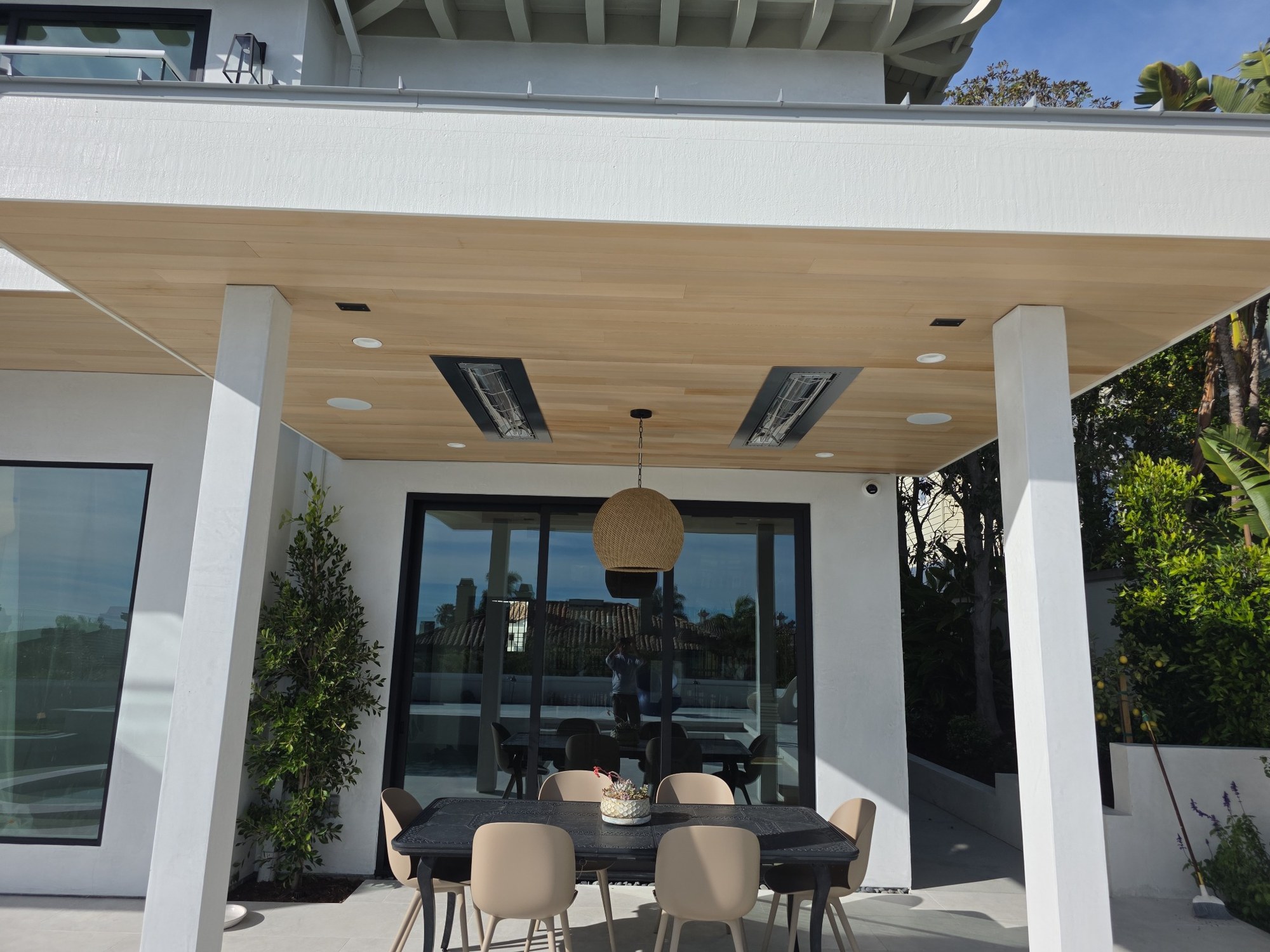 Covered outdoor living area with wood ceiling, recessed lighting, dining space, and large glass door 