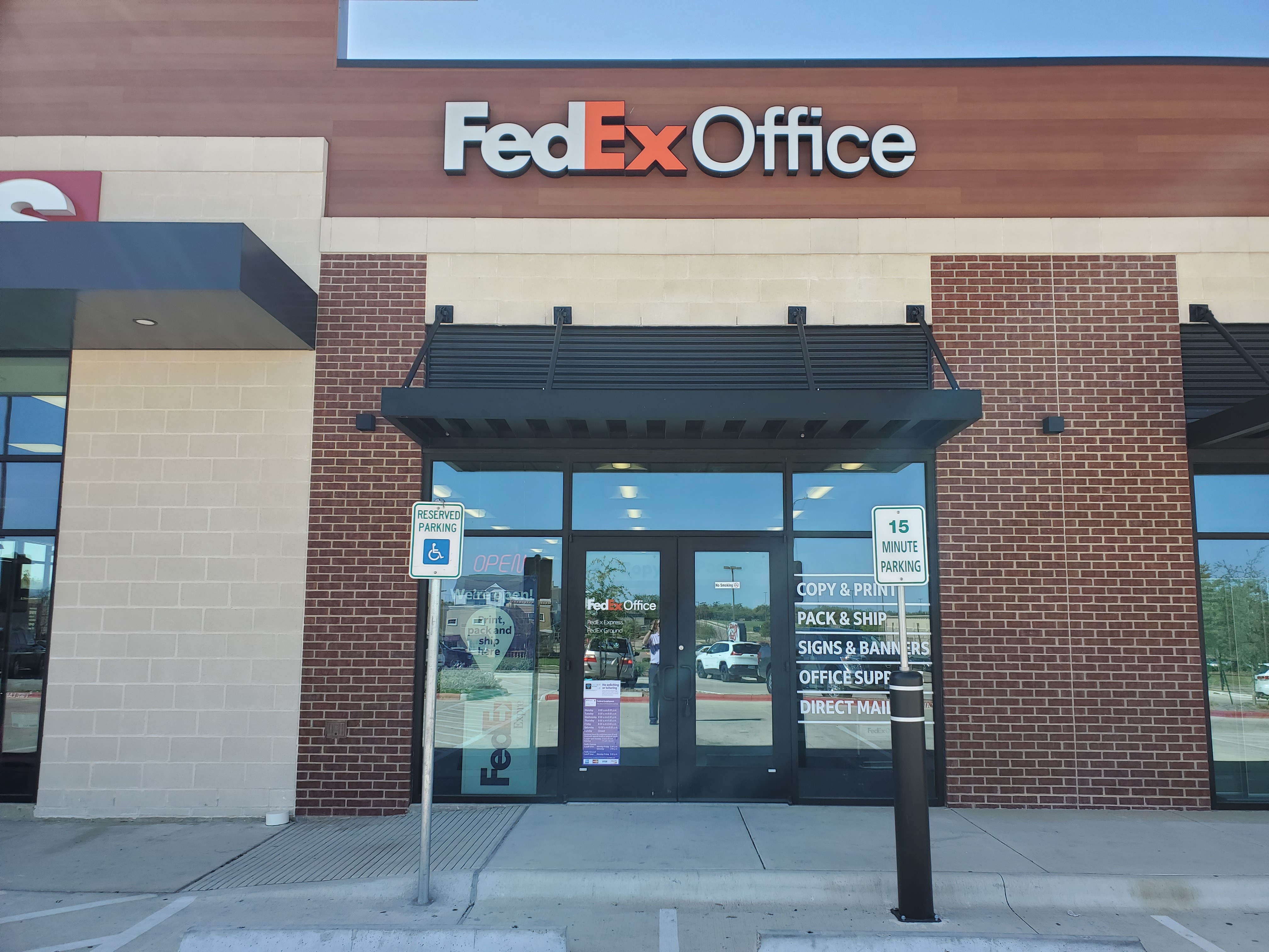 Close-up of FedEx Office storefront in College Station Texas showing entrance doors, signage, and customer access for print and shipping services.