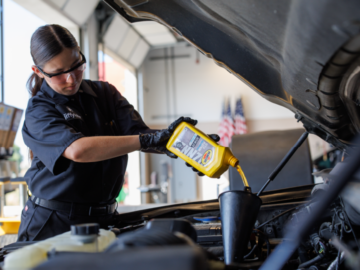 female tech pouring Pennzoil oil into car