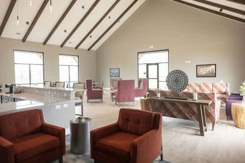 A living room with a red chair and a brown couch.