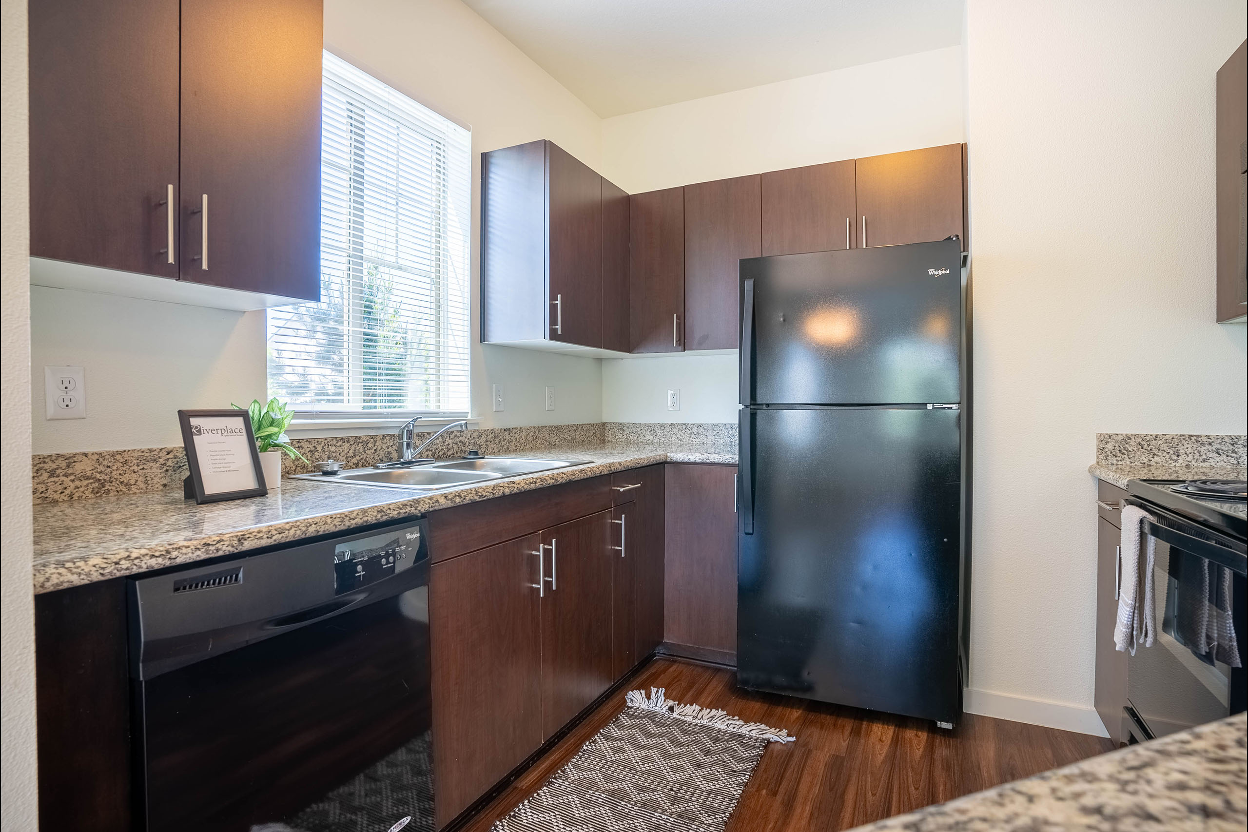 A kitchen with a black fridge and wooden cabinets.