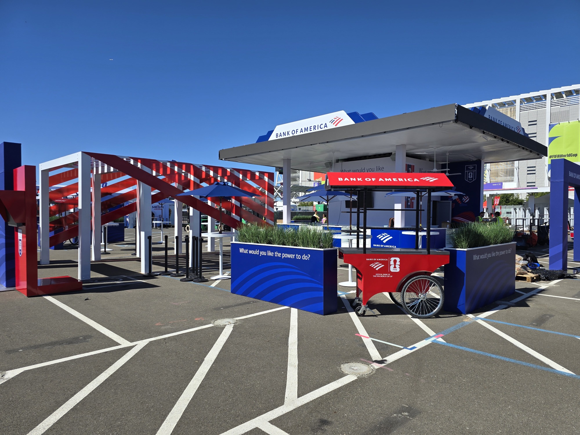 Custom outdoor event display featuring the Bank of America pavilion, branded cart, decorative planters, and bold red, white, and blue structural elements.