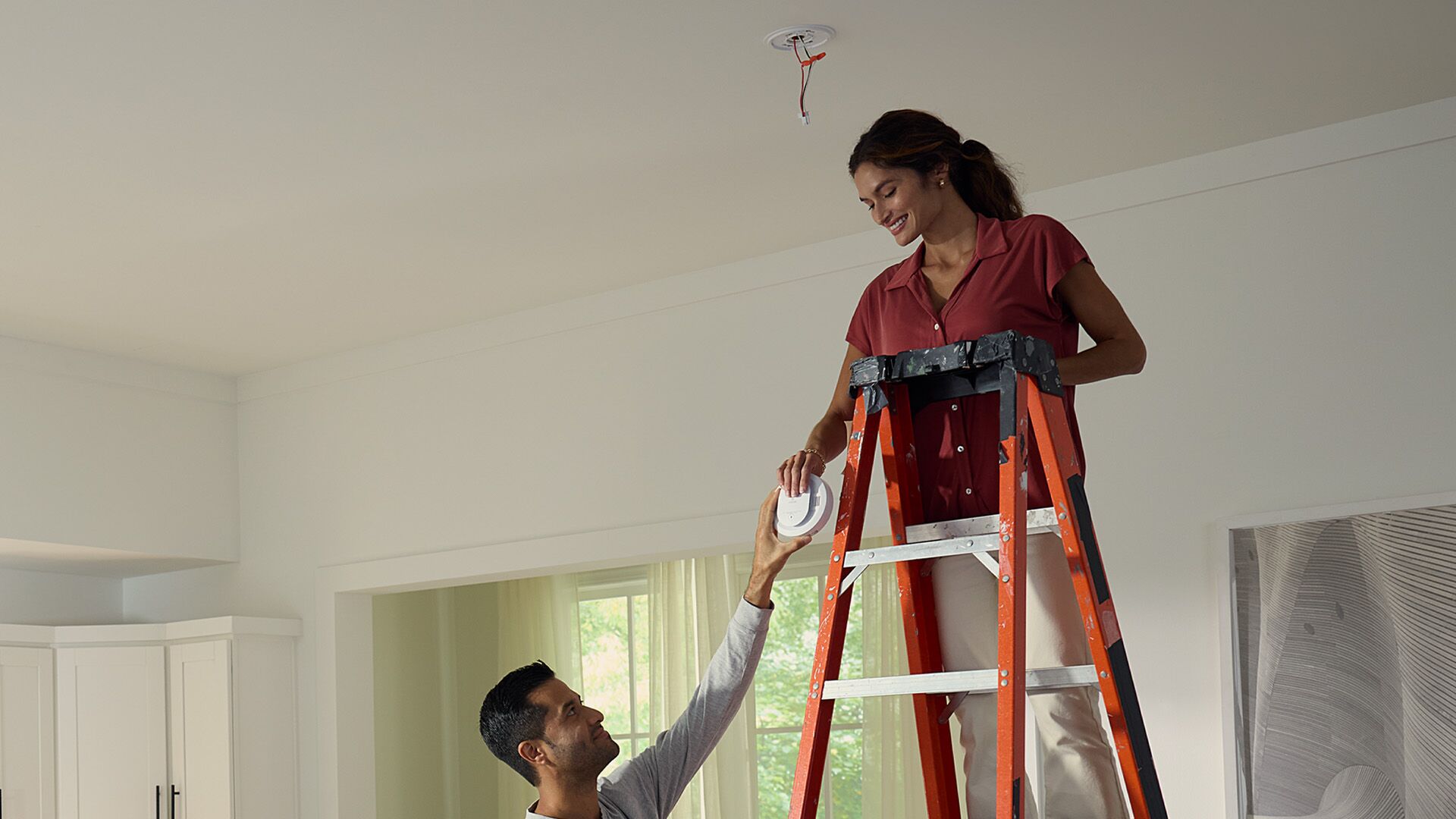 Couple installing a carbon monoxide detector on their ceiling