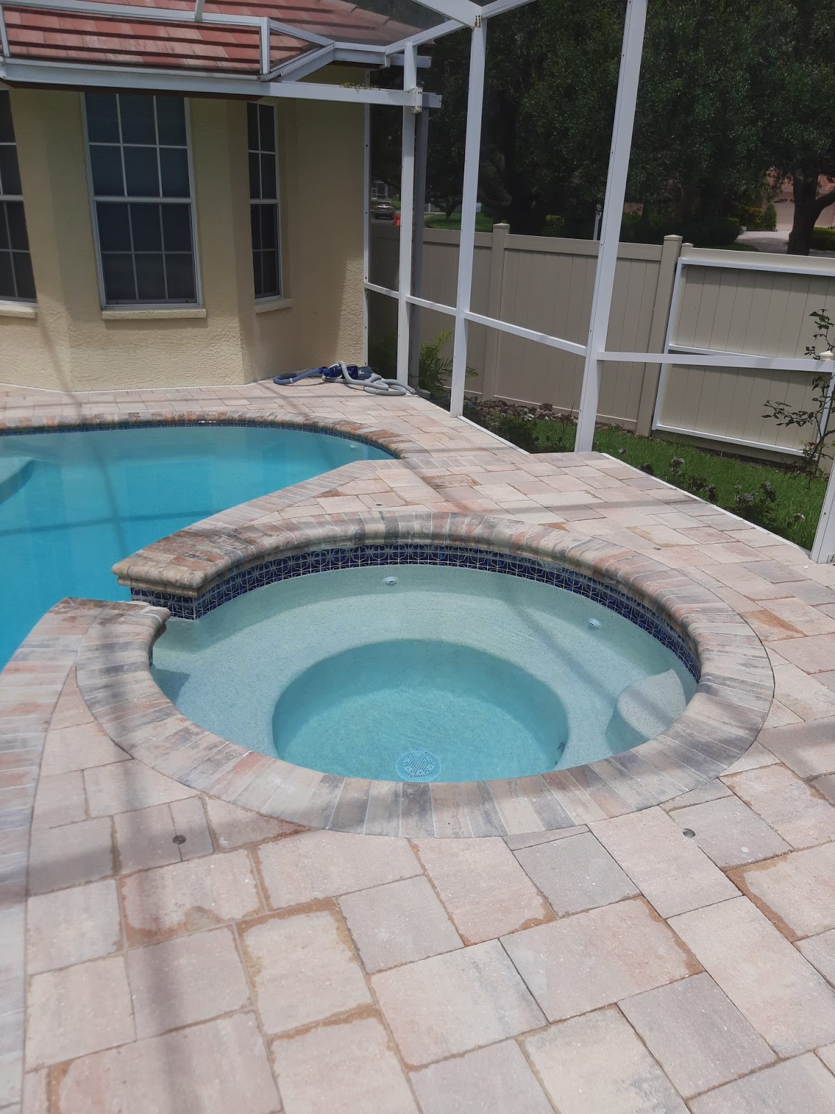 Backyard swimming pool with an attached round spa, light stone paver decking, and a screened patio enclosure.
Select 83 more words to run Humanizer.