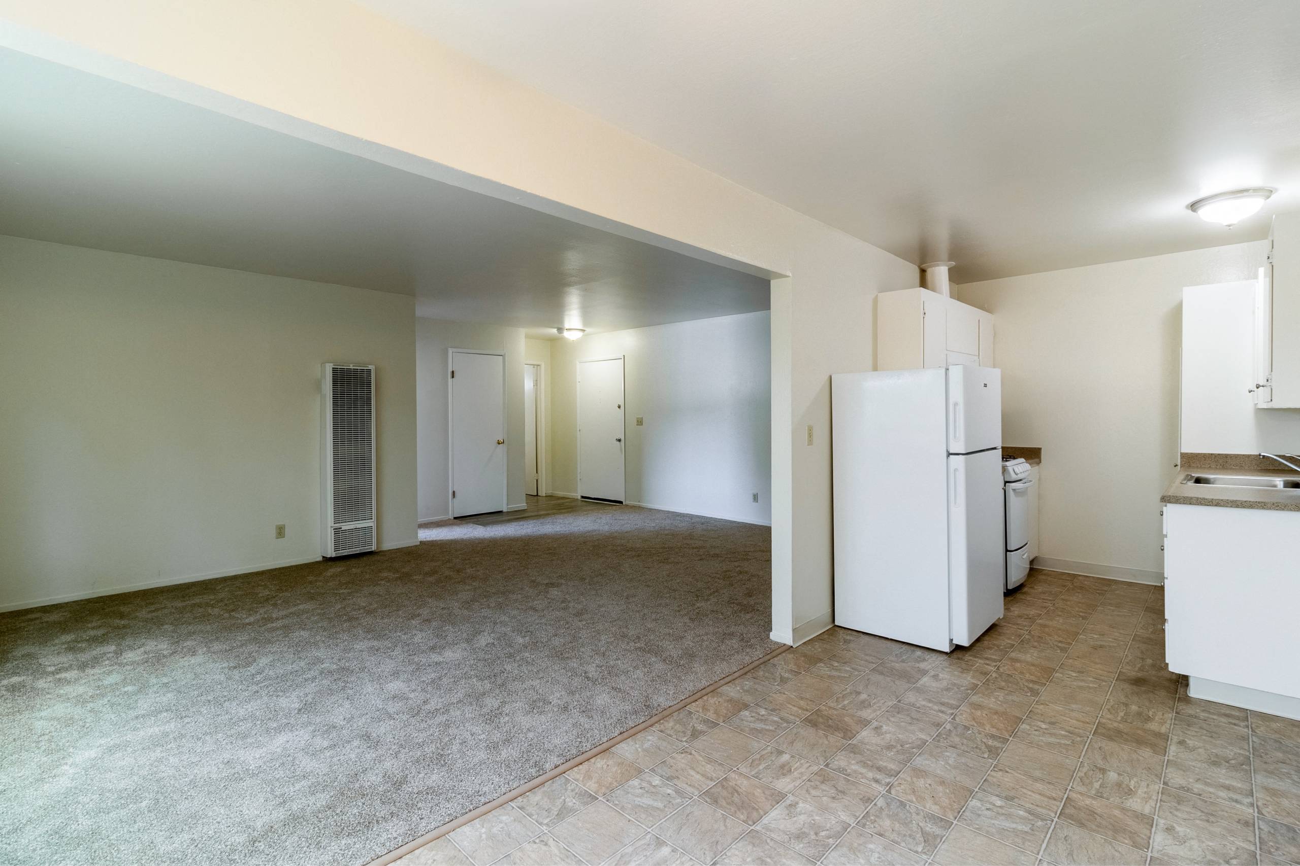 A kitchen area with a refrigerator, sink, and cabinets.