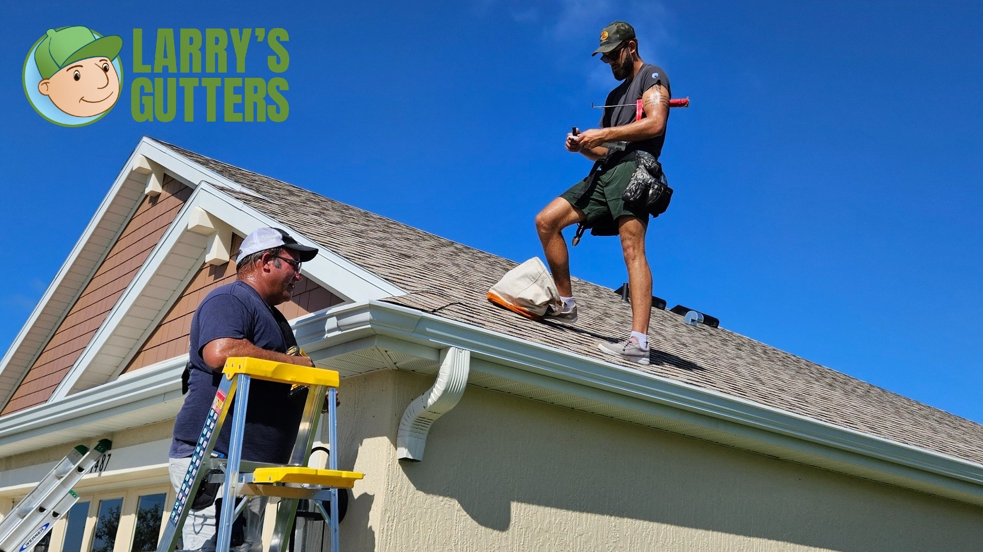 Two men work on cleaning a house gutter under a clear blue sky. One stands on a ladder, the other on the roof. "Larry's Gutters" logo is visible.