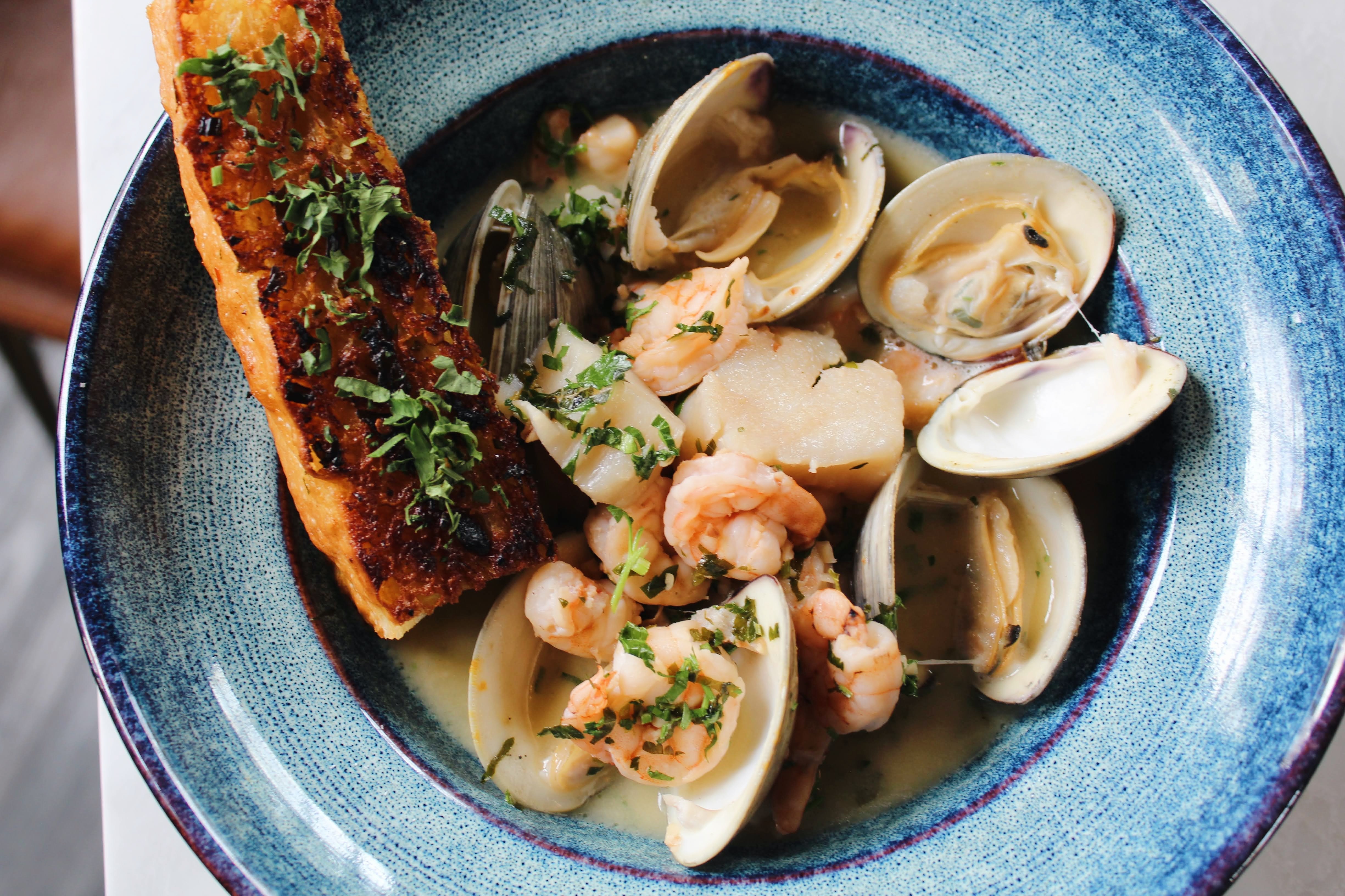 Italian Seafood Scampi — scallops, shrimp, and clams simmered in white wine, lemon, garlic, and butter with fine herbs, served with warm grilled focaccia.