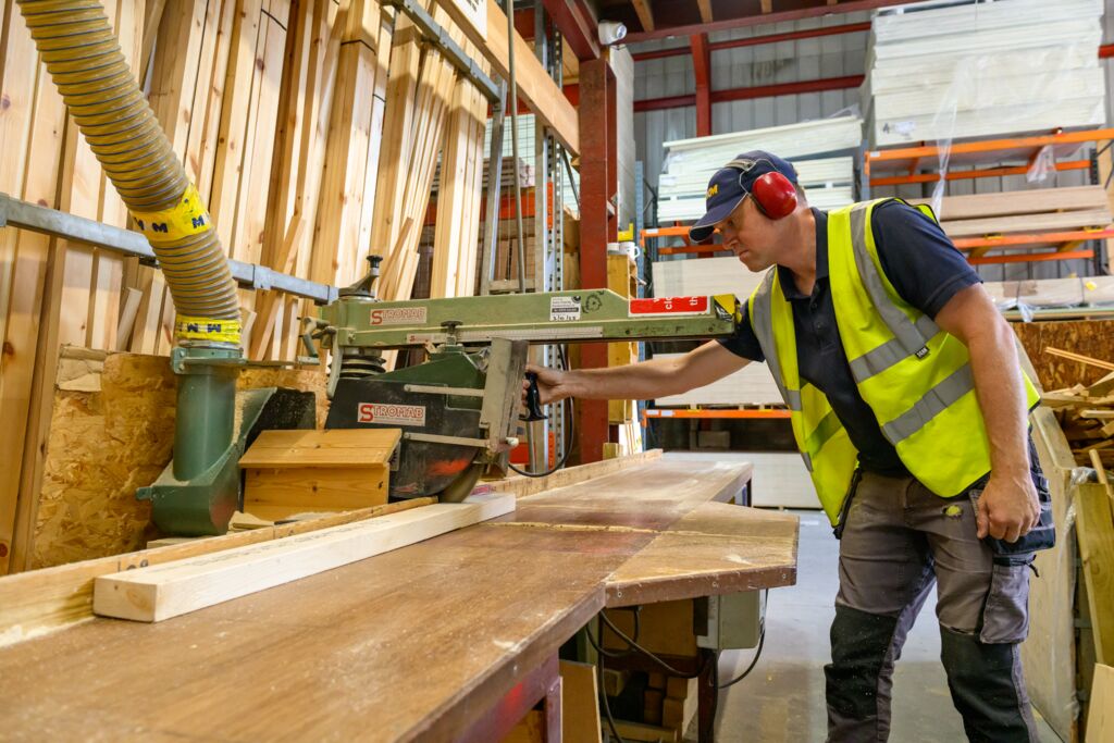 Image of man cutting timber in hi-vis