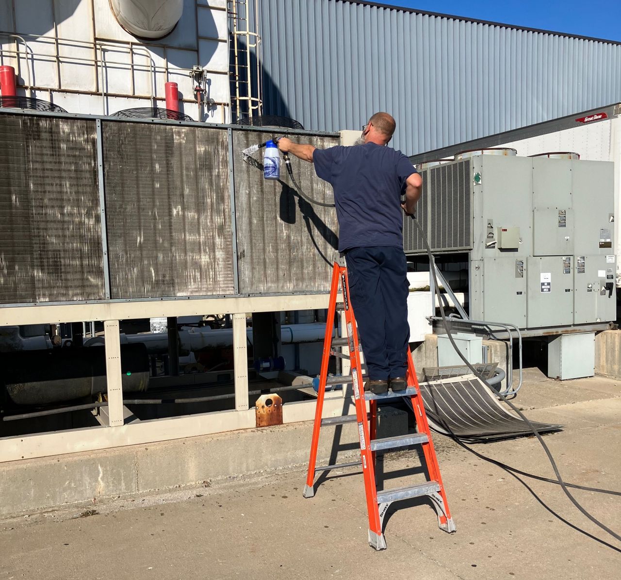 Technician cleaning outdoor commercial AC coils