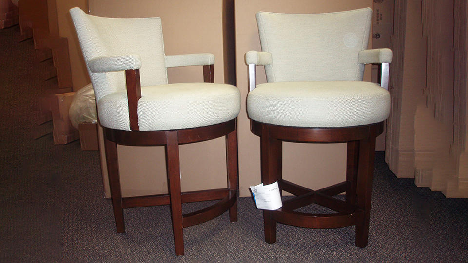 two richly-crafted bar stools with chair backs and arm rests from an estate sale, ready for packing