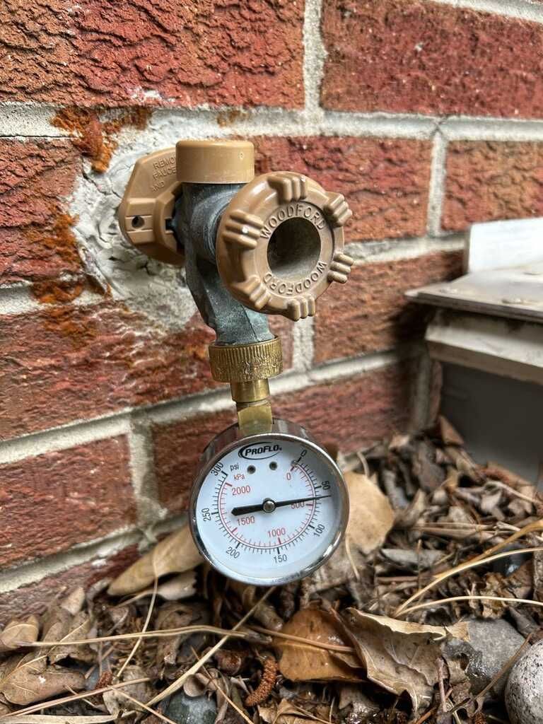 Outdoor hose bib features a freeze resistant faucet and attached pressure gauge mounted against a br 